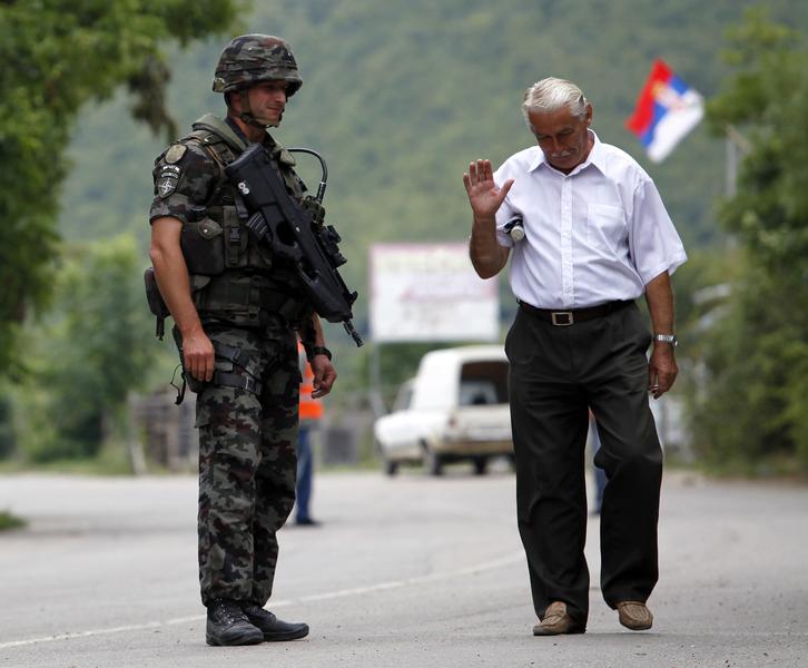 Un sarb din nordul Kosovo trece pe langa un soldat Kfor (NATO), Foto: Reuters