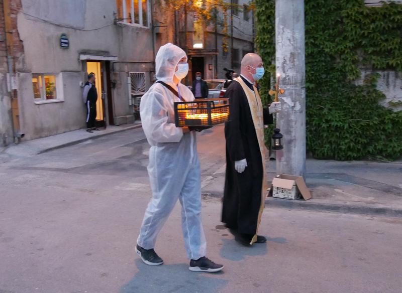 Preot și voluntar de la biserică împart lumina de Înviere, Paște 2020, Foto: Gabriel Bejan