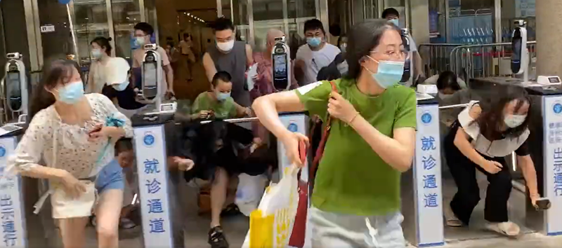 Oameni trecand pe sub turnicheti pentru a iesi din spital la Shanghai, Foto: Captura video