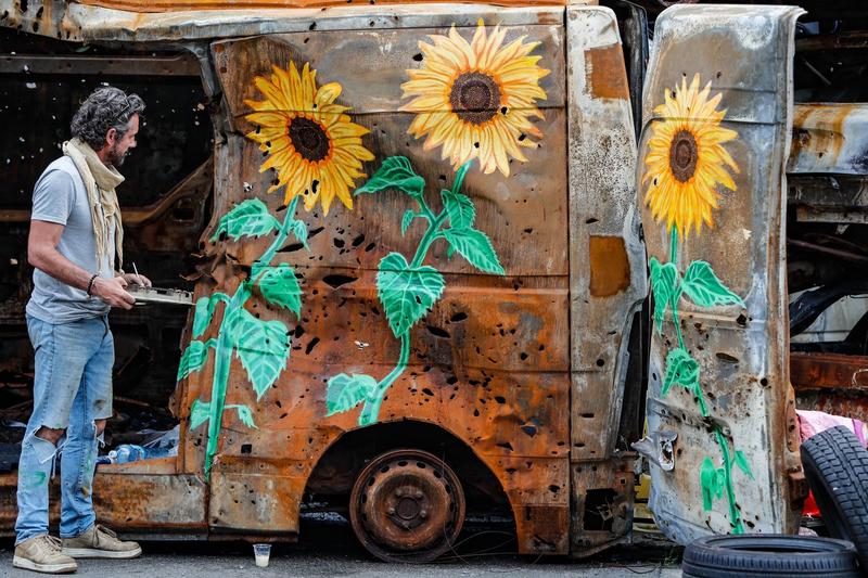 Război în Ucraina: Un artist pictează floarea-soarelui pe vehicule distruse în atacuri rusești, în Irpin, regiunea Kiev, Foto: Daniel Ceng Shou-Yi / Zuma Press / Profimedia