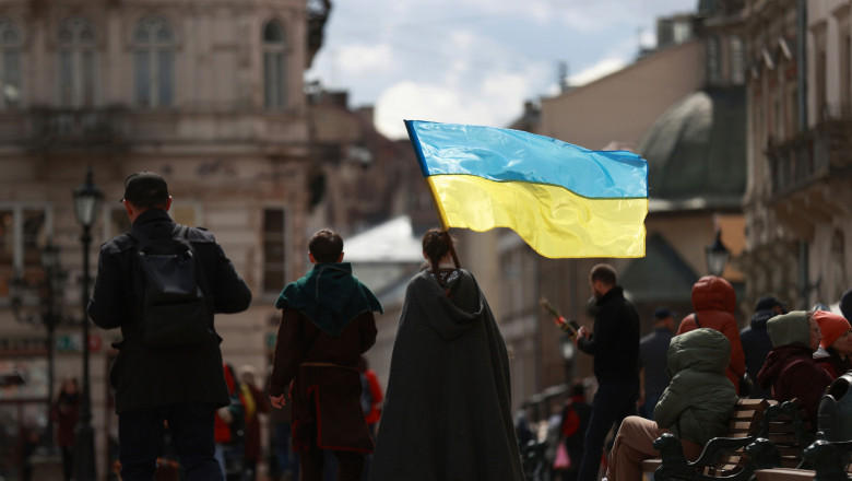 Câțiva ucraineni flutură steagul ucrainean într-o piață din centrul orașului Liov, din vestul Ucrainei, în timp ce războiul continuă, Foto: Profimedia Images