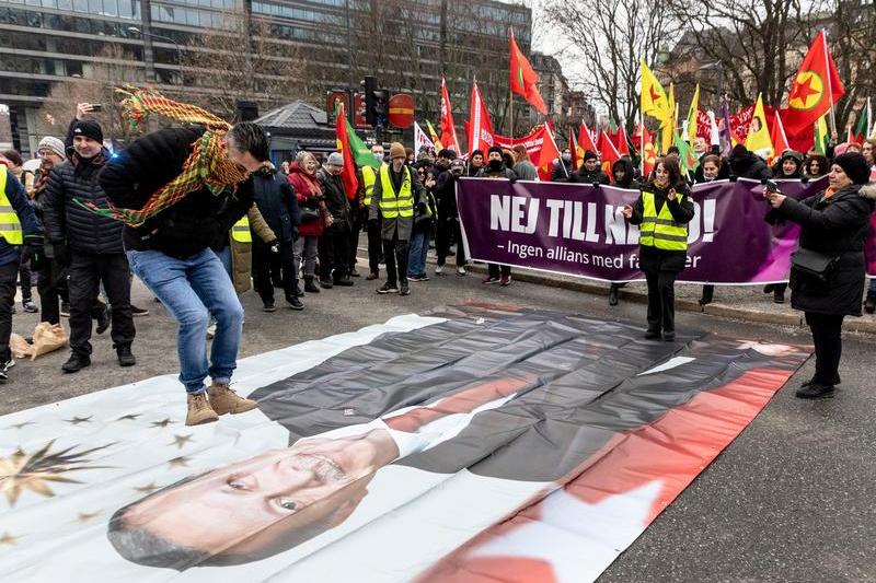 Un protestatar sare peste o pancarta cu chipul lui Erdogan in Suedia, Foto: Christine Olsson/TT / AP / Profimedia