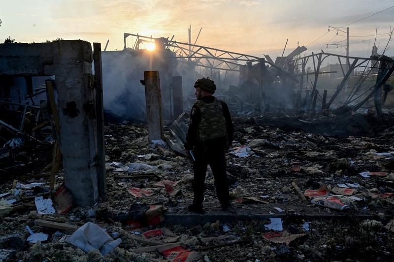 Un polițist ucrainean cercetează o zonă industrială din Kiev, după atacul masiv lansat de Rusia, Foto: Sergei SUPINSKY / AFP / Profimedia