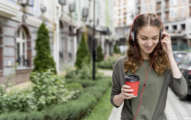 Femeie care bea cafea și ascultă muzică, Foto: freepik.com