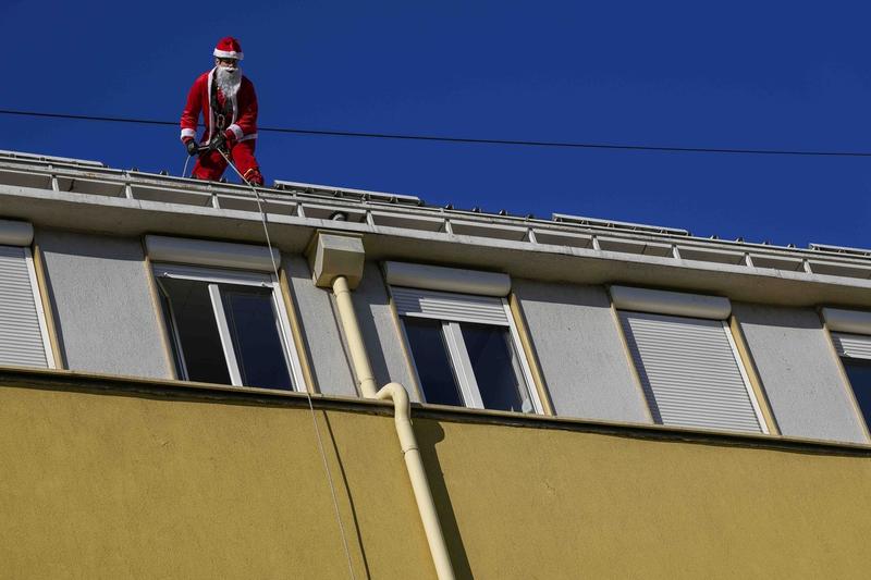 Un bărbat costumat în Moș Crăciun pe o clădire, Foto: Darko Vojinovic / AP / Profimedia