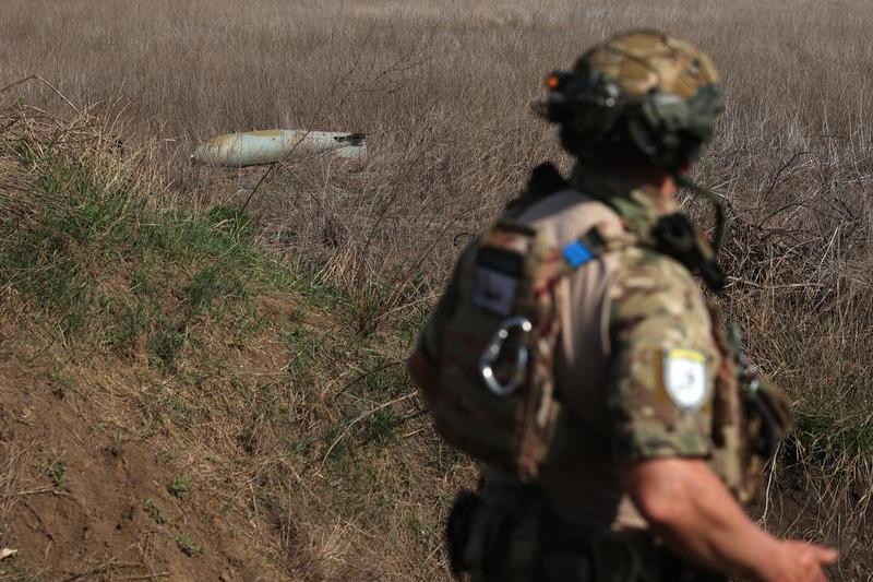 Soldat ucrainean care se uită la o bombă rusească FAB-500 neexplodată, Foto: Anatolii Stepanov / AFP / Profimedia