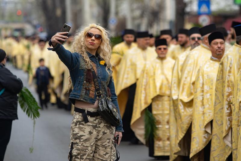O tânără își face un selfie lângă e procesiune de Paște în București, Foto: Lucian Alecu / Shutterstock Editorial / Profimedia