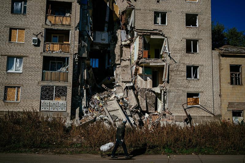 Un localnic trece prin fata unei cladiri distruse de bombardamente in Ucraina, Foto: Dimitar DILKOFF / AFP / Profimedia