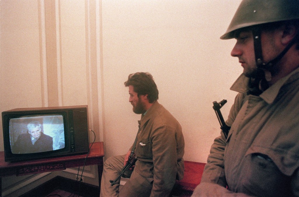 În sediul ocupat al Comitetului Central al Partidului Comunist, soldați români privesc transmisia procesului soților Ceaușescu, decembrie 1989. Foto: JOEL ROBINE / AFP / Profimedia