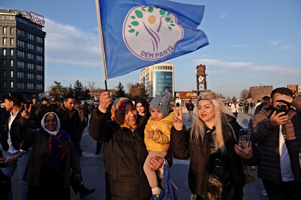 O femeie kurdă ridică steagul partidului pro-kurd în timp de ascultă apelul liderului PKK Abdullah Öcalan, citit în Diyarbakır, Turcia, 27 februarie 2025. Foto: SOPA Images Limited / Alamy / Profimedia