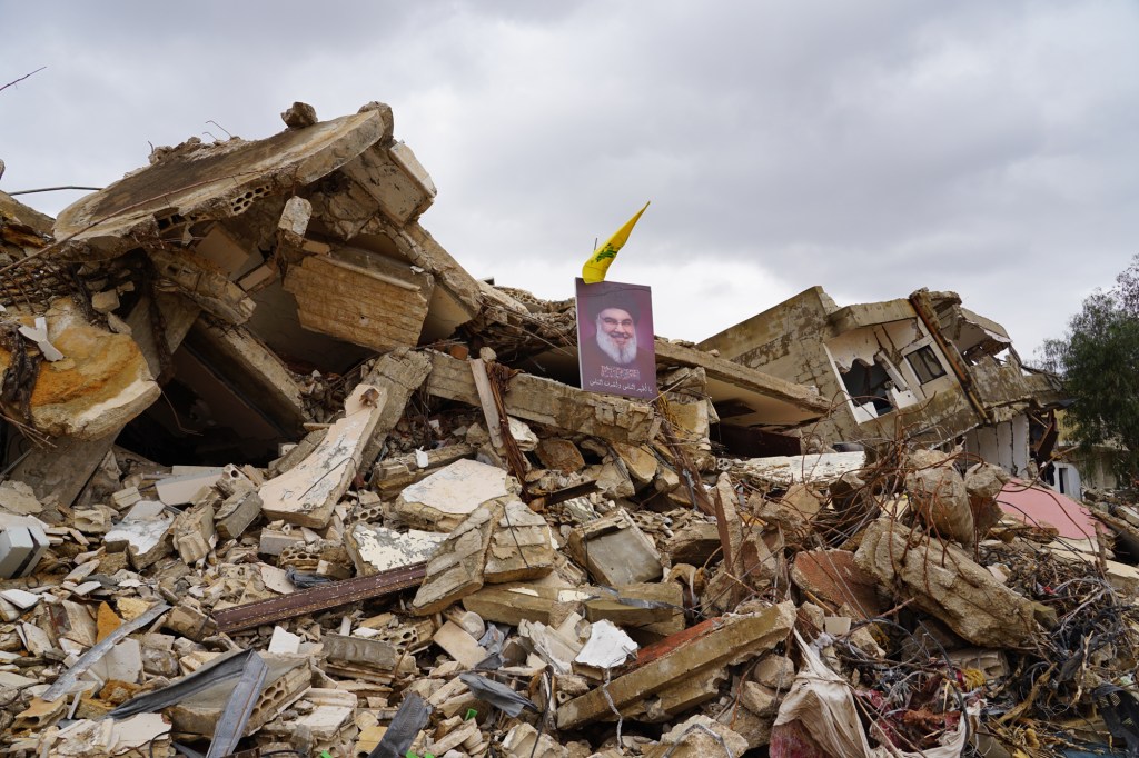 Un potret al fostului lider Hezbollah, Hassan Nasrallah, pe ruinele unei case distruse din Ayta al-Shaab