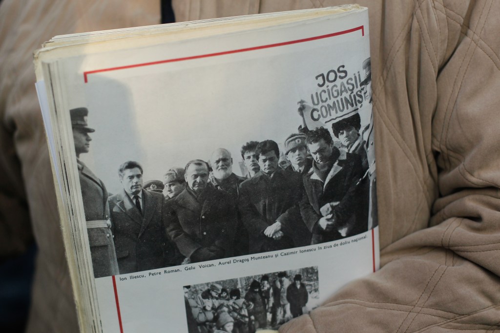 O femeie ține la piept o publicație în care este vizibilă fotografia fostului președinte Ion Iliescu, în timpul depunerii de coroane de flori în memoria Eroilor Martiri care au murit pentru victoria Revoluției din Decembrie 1989, în Cimitirul Eroilor Revoluției, București, luni, 21 decembrie 2015. Inquam Photos / Octav Ganea