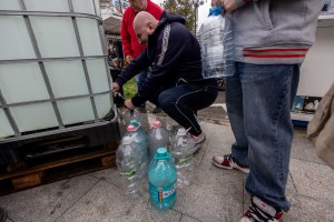 Mai multe persoane așteaptă la rând pentru a umple sticle cu apă potabilă, în orașul Câmpina, luni, 1 decembrie 2025 | Foto:  Inquam Photos / Ovidiu Micsik