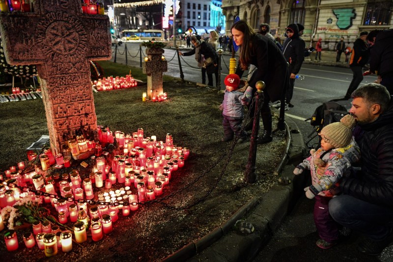 Mai mulți oameni aprind lumânări în memoria victimelor Revoluției, în Piața Universității, București. Foto: Daniel Mihăilescu / AFP / Profimedia