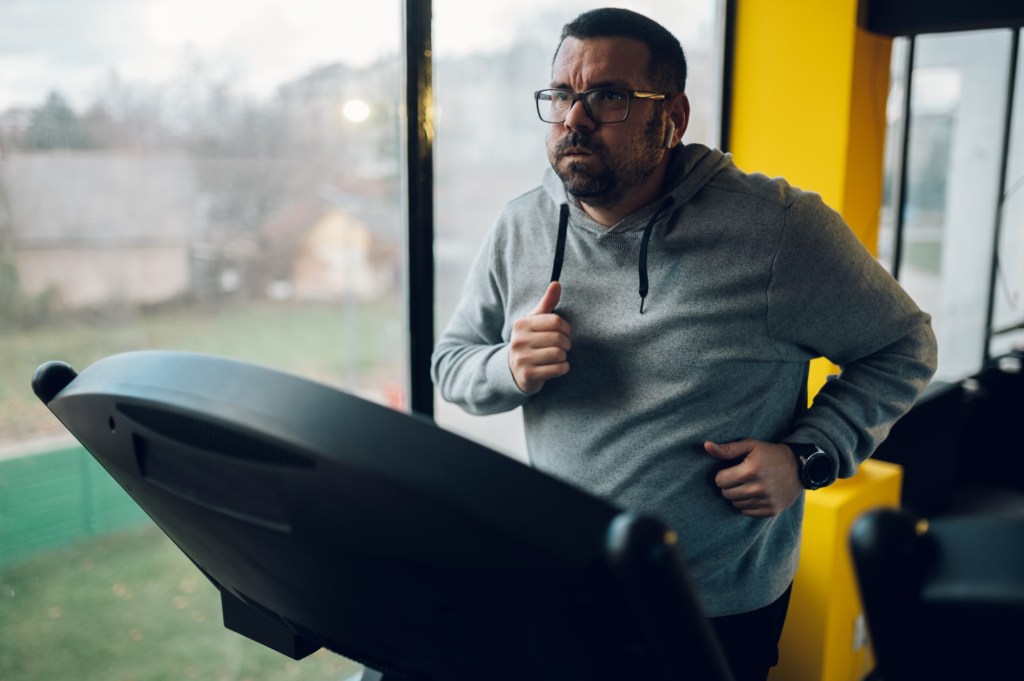 bărbat supraponderal aleargă pe banda de alergare