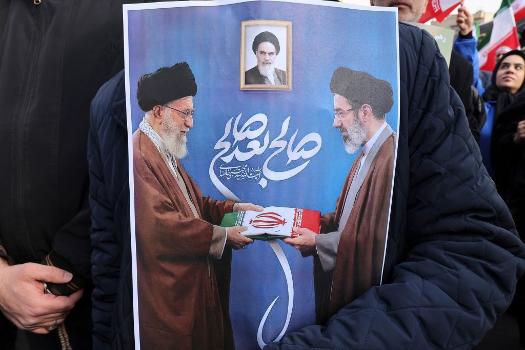 Un susținător al regimului actual Iranian ține un poster cu fostul lider suprem Ali Khamenei (stânga) și actualul ayatollah Mojtaba Khamenei, la un miting in Teheran, 9 martie 2026. Foto: Atta KENARE / AFP / Profimedia