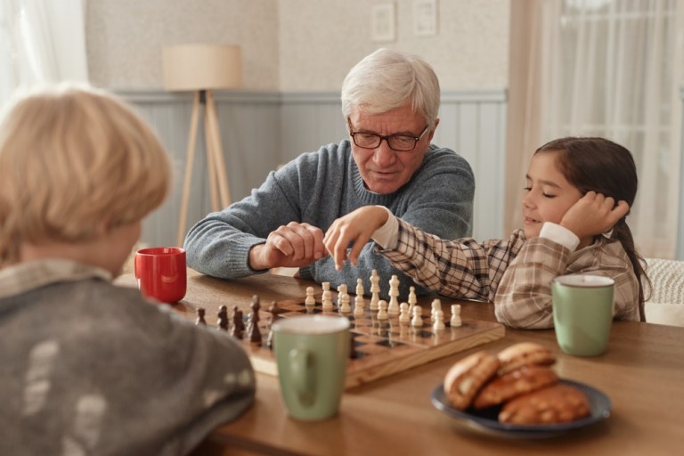 bărbat în vârstă joacă șah cu o fetiță