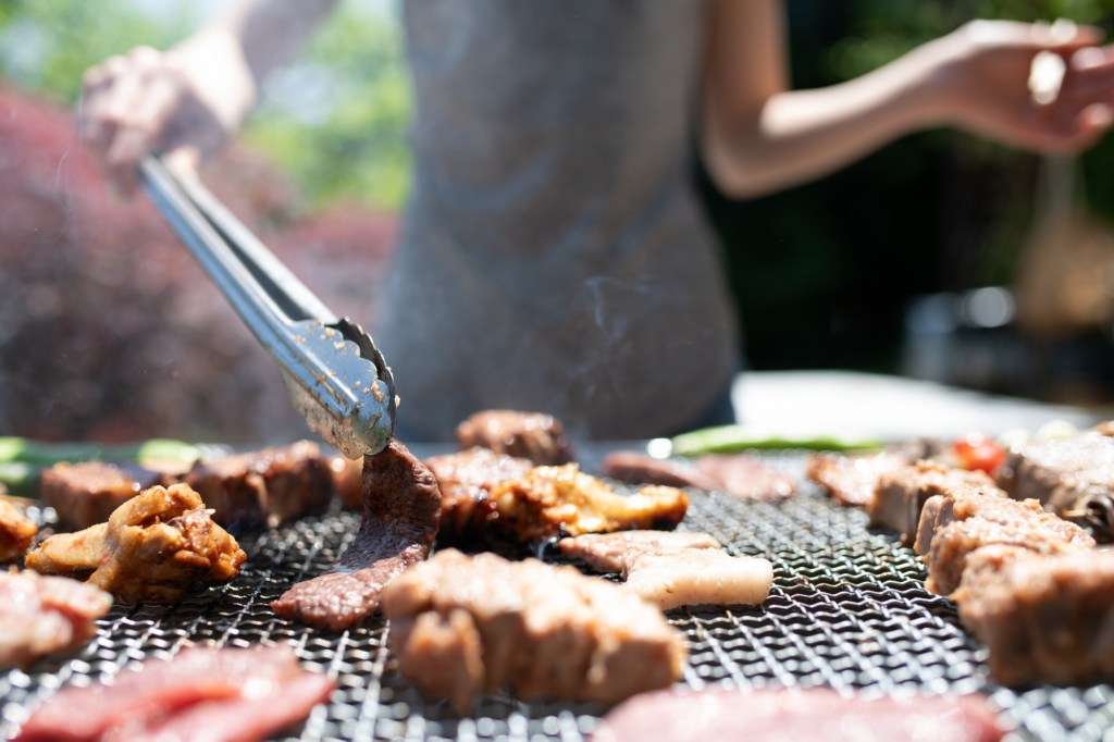 femeie care gătește carne pe grătar