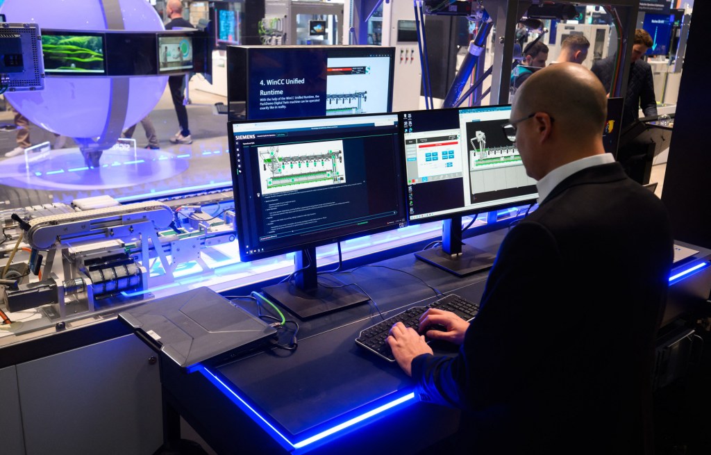 Un angajat din industria farmaceutică operează o mașinărie de producție cu ajutorul sistemului de inteligență artificială Siemens Co-Pilot, la târgul industrial Messe 2025 din Hanover. Foto: JULIAN STRATENSCHULTE / AFP / Profimedia