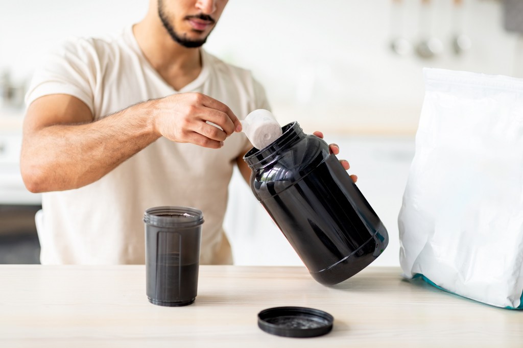 un bărbat își prepară un shake din pudră proteică pentru masa musculară