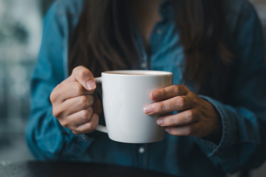 femeie bea o cană mare de cafea