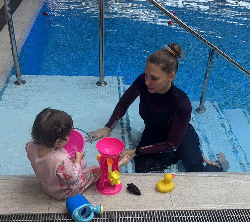 Andreea-Silvia Drăgan, instructor de înot și psiholog, alături de o fetiță care refuză să intre în apă. FOTO: Arhiva personală