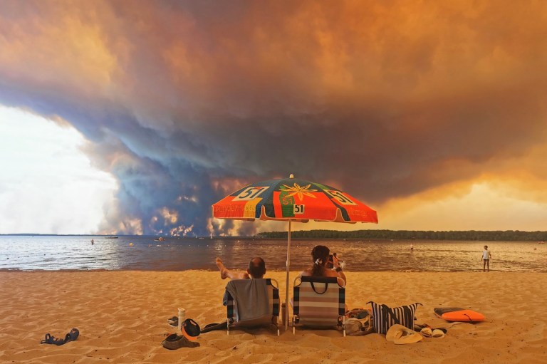 Două persoane stau pe plaja Moutchic, de pe malul lacului Lacanau, în timp ce zona este amenințată de incendiile din Gironde, din apropiere de Bordeaux Foto: Profimedia
