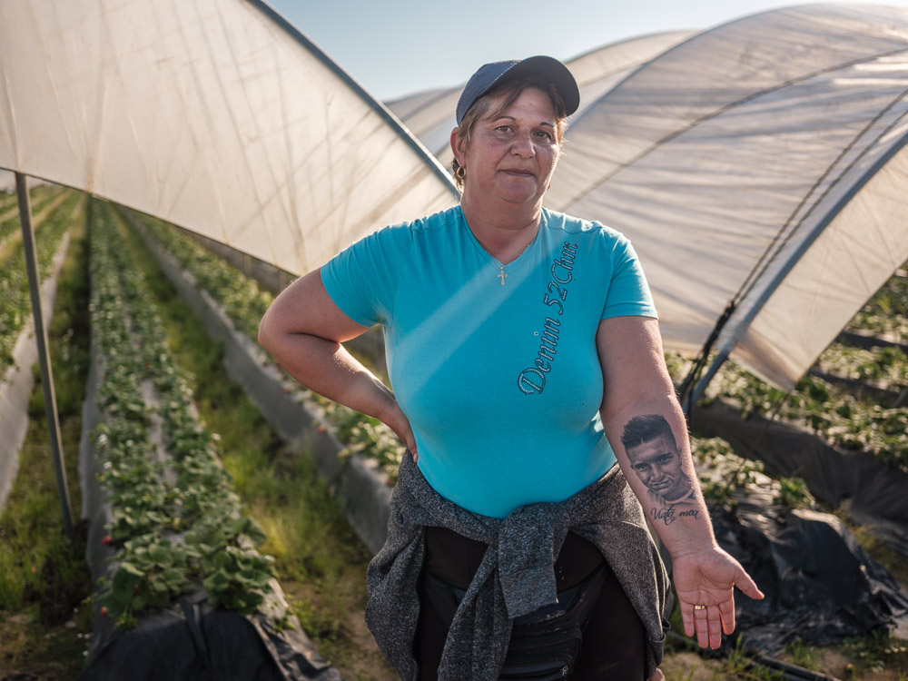 Corina, 45 de ani, a plecat din România în 2003, când băiatul ei, Ciprian, avea 3 ani. L-a lăsat în grija bunicilor și s-a dus în Spania, în Palos de la Frontera, ca să lucreze la căpșuni. Corina era tehnician veterinar în Râmnicu Sărat, dar câștiga așa de puțin încât banii nu-i ajungeau să crească un copil. Tatăl băiatului o părăsise când era însărcinată în luna a șaptea. După ani de muncă, a reușit să ridice în România, în satul din care a plecat, două case: una pentru ea, una pentru fiul ei. Băiatul ei a murit pe neașteptate la 17 ani, după ce a făcut un infarct. Corina și-a tatuat pe mână chipul fiului ei ca să-l simtă mereu aproape de ea. Palos de la Frontera, Spania, 10 februarie 2020  Foto: Cosmin Bumbuț / Teleleu.eu
