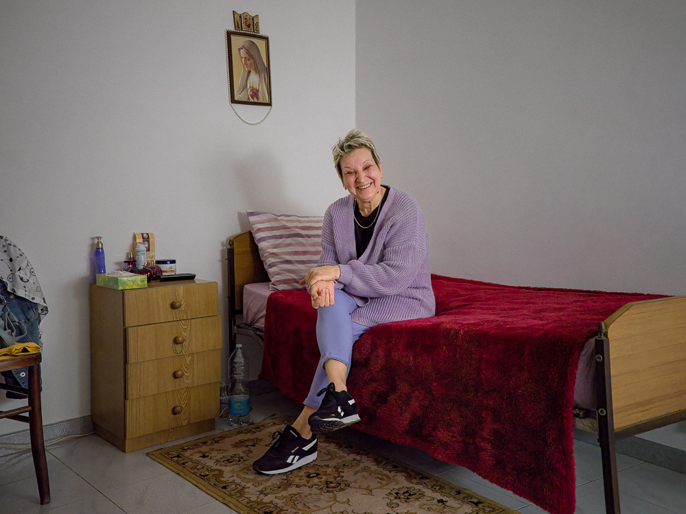 Eugenia, 54 de ani, îngrijește persoane în vârstă în Italia. Fotografia a fost făcută în casa unei bătrâne de 94 de ani din Leverano, provincia Lecce, în camera în care Eugenia este cazată. Românca a plecat din țară ca să scape dintr-o relație abuzivă — se temea că soțul ei o va ucide. Italia, 3 mai 2022 Foto: Cosmin Bumbuț / Teleleu