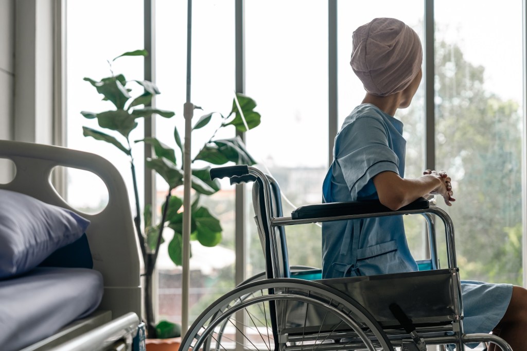 o pacientă cu cancer în spital privește pe geam