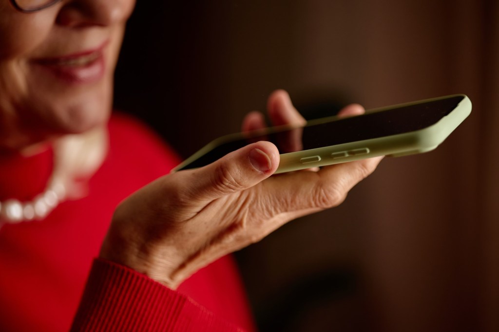 femeie în vârstă înregistrează mesaj audio pe telefon